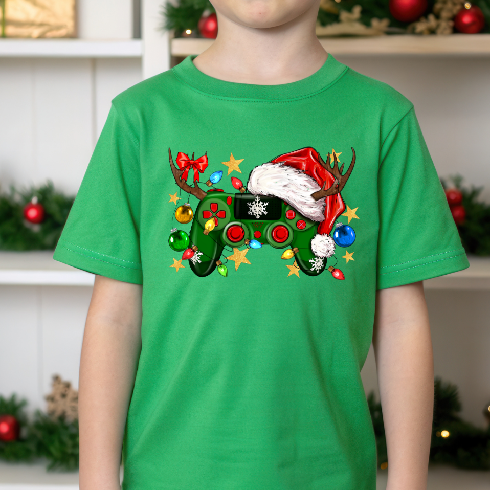 Child wearing a green t-shirt with a Christmas-themed design in front of a decorated background.