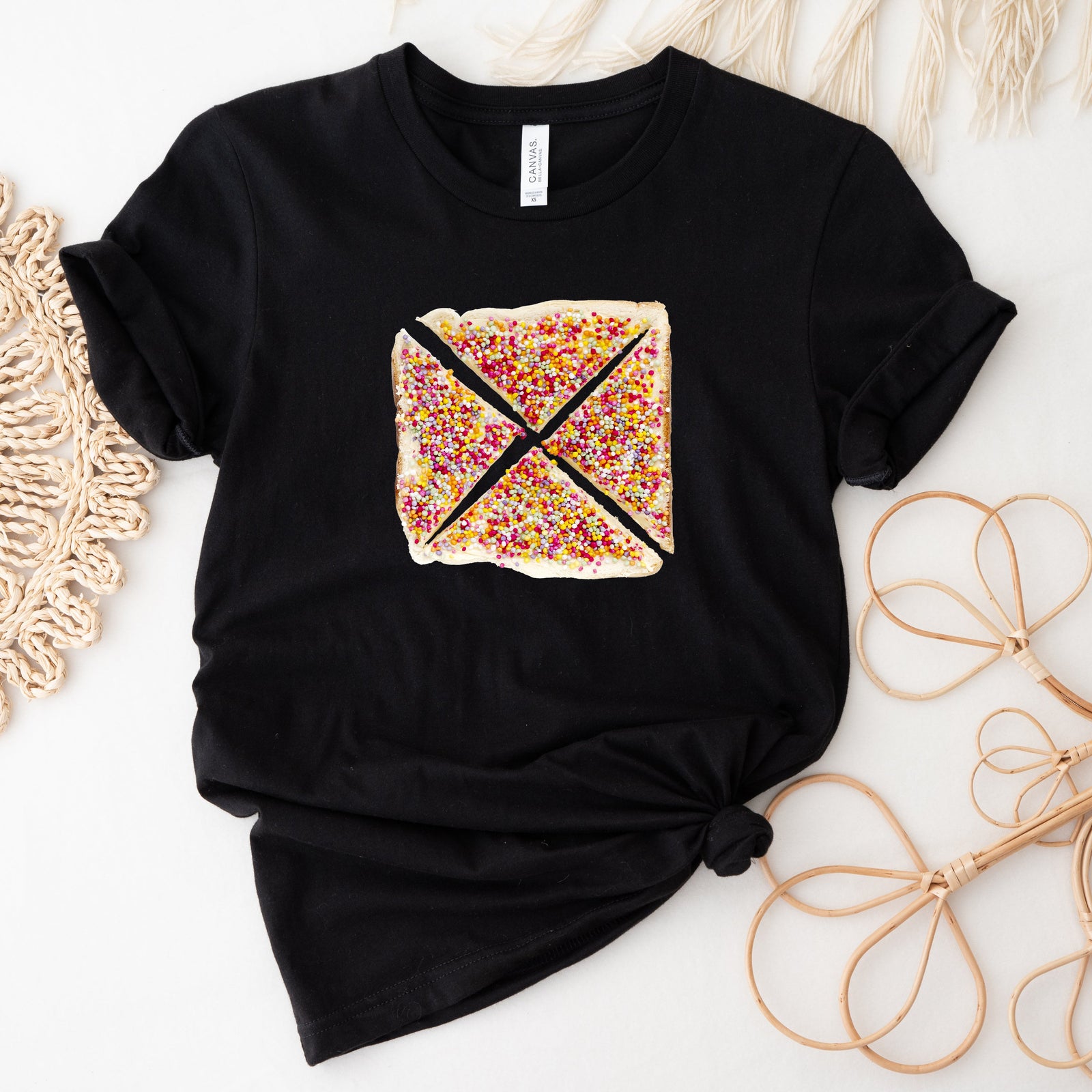 Black t-shirt with a colorful graphic design on a white surface with decorative elements.
