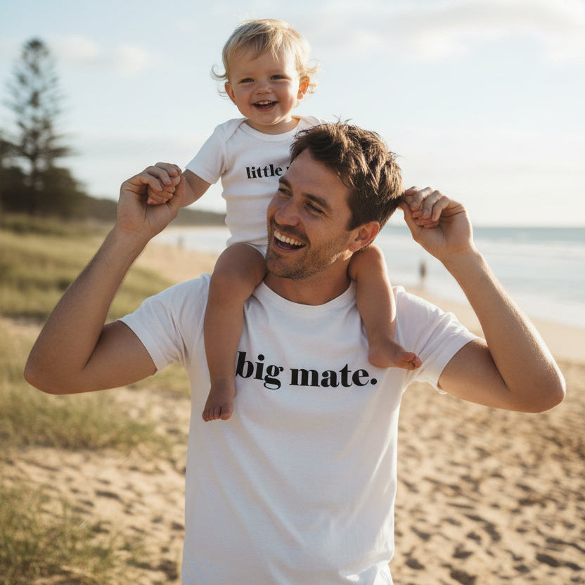Man holding a child on his shoulders at the beach with 'big mate' t-shirt and 'little mate' bodysuit