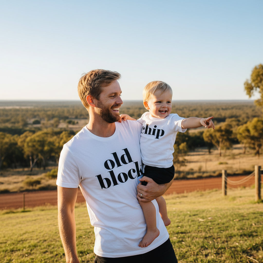 Father and son in white t-shirts. Father's reads 'old block' and child's reads 'chip'