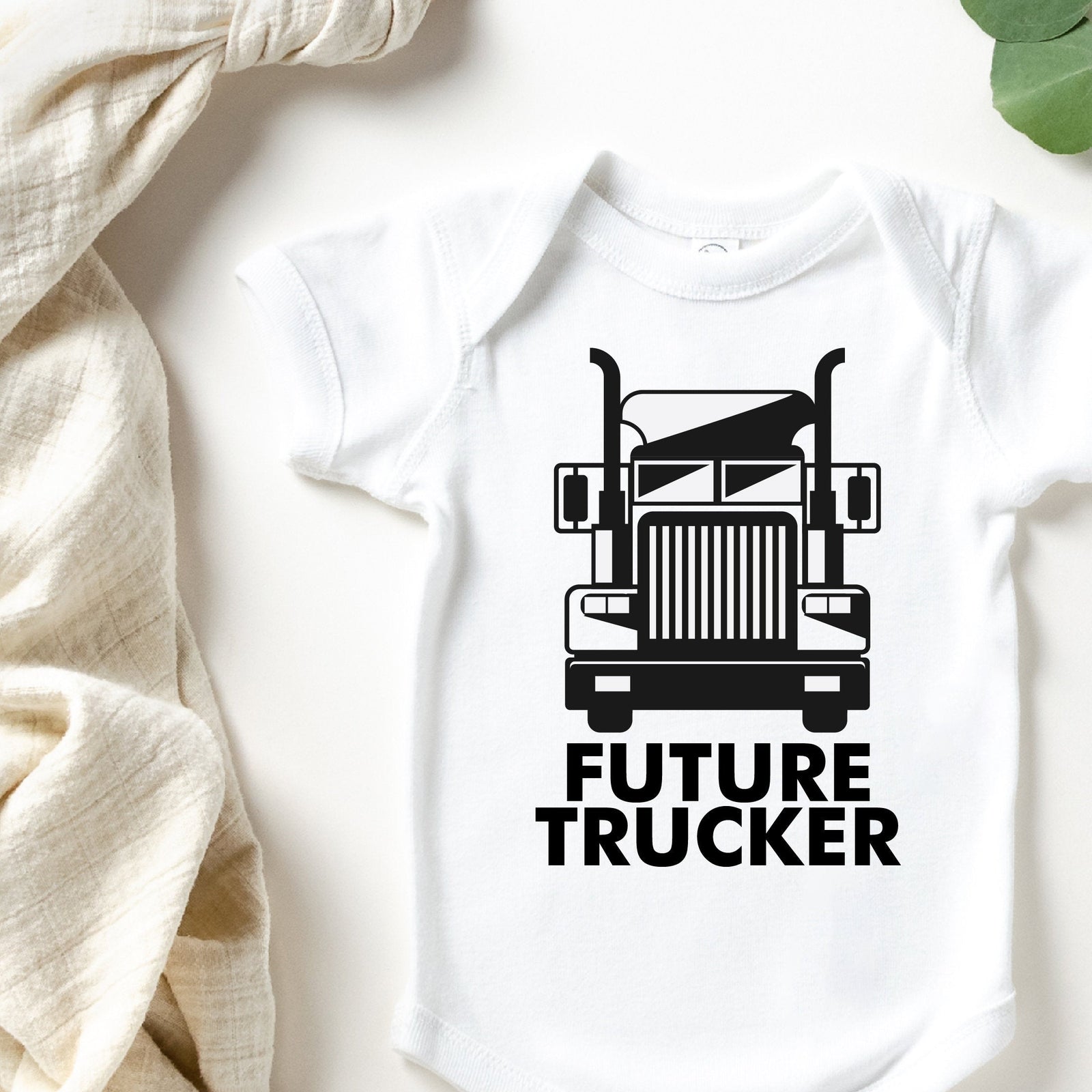 White baby bodysuit with a black truck illustration and the words Future Trucker.
