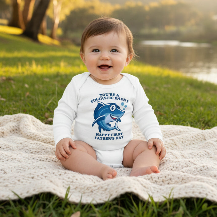 White baby bodysuit with a cartoon shark and text reading You're A Fin-Tastic Daddy, Happy First Father's Day.