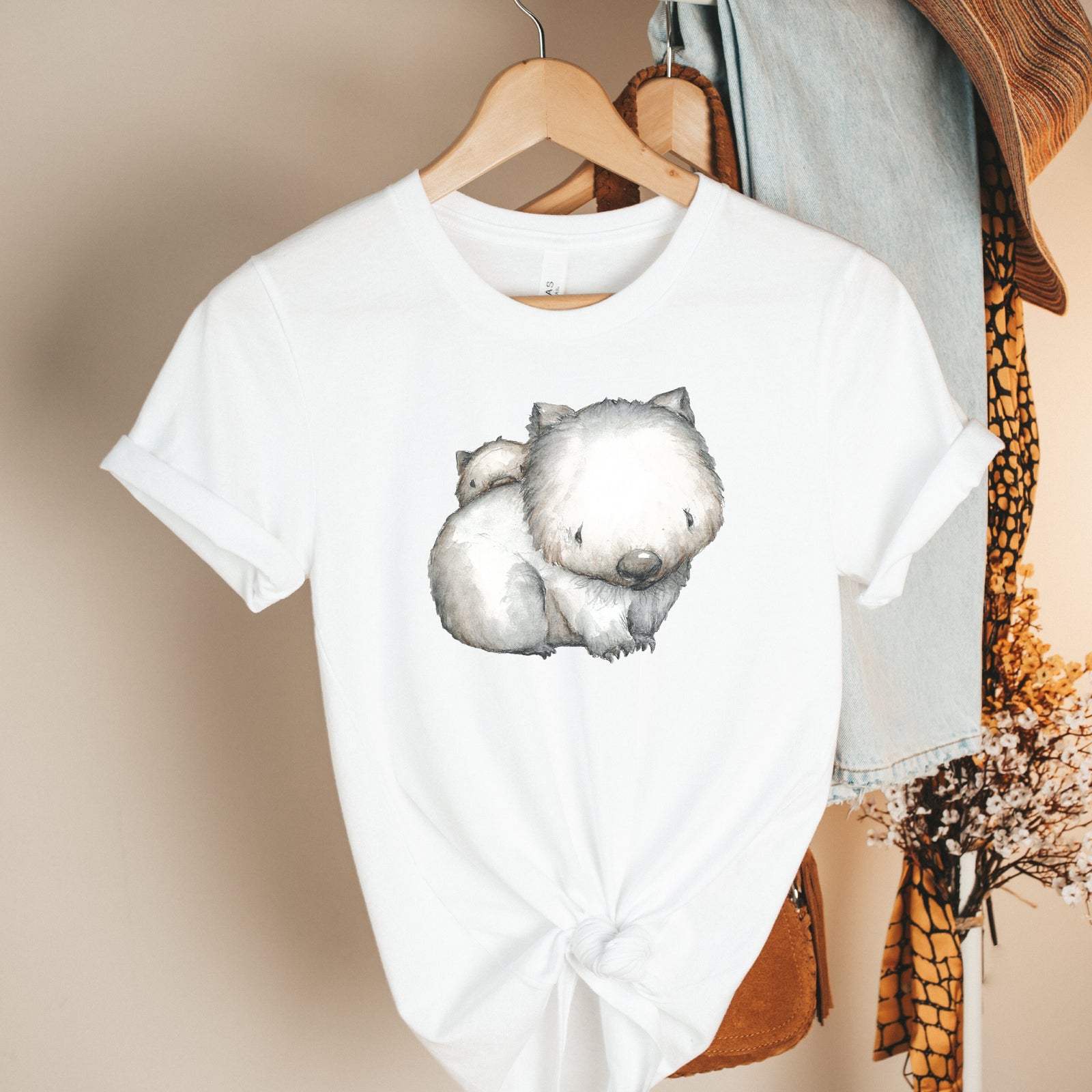 White t-shirt with a softly illustrated mother wombat and her baby resting on her back.