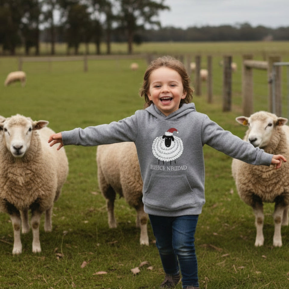 Smiling child in a grey Fleece Navidad Christmas hoodie running through a paddock with sheep