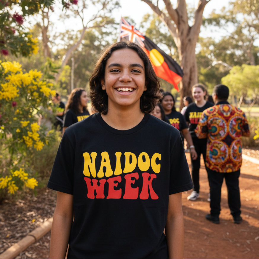 Black t-shirt with 'NAIDOC WEEK' text in yellow and red on a white background