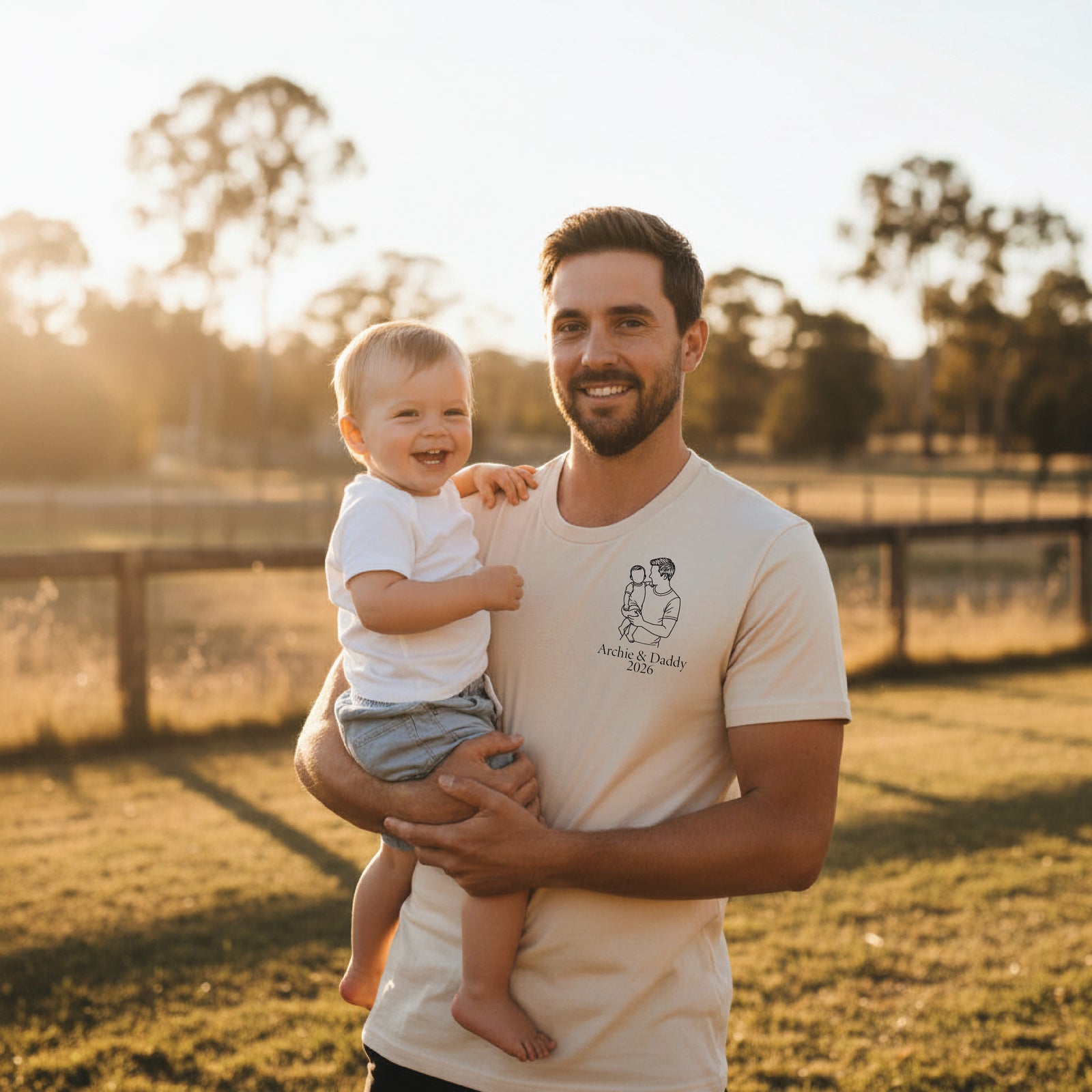 Natural t-shirt with a line-art drawing of a father holding a child and personalised names and year.