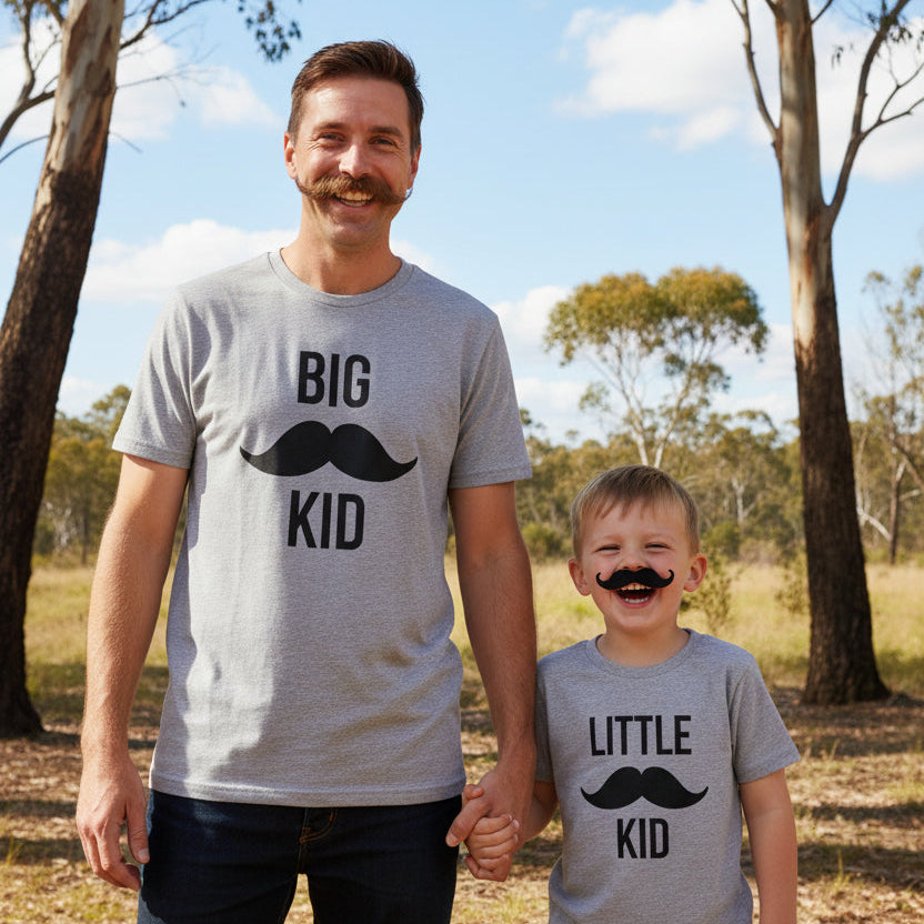 Dad and son wearing matching grey t-shirts with moustache designs reading Big Kid and Little Kid.
