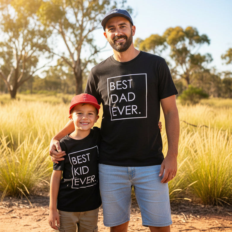 Dad and young son wearing matching black Best Dad Ever and Best Kid Ever t-shirts outdoors