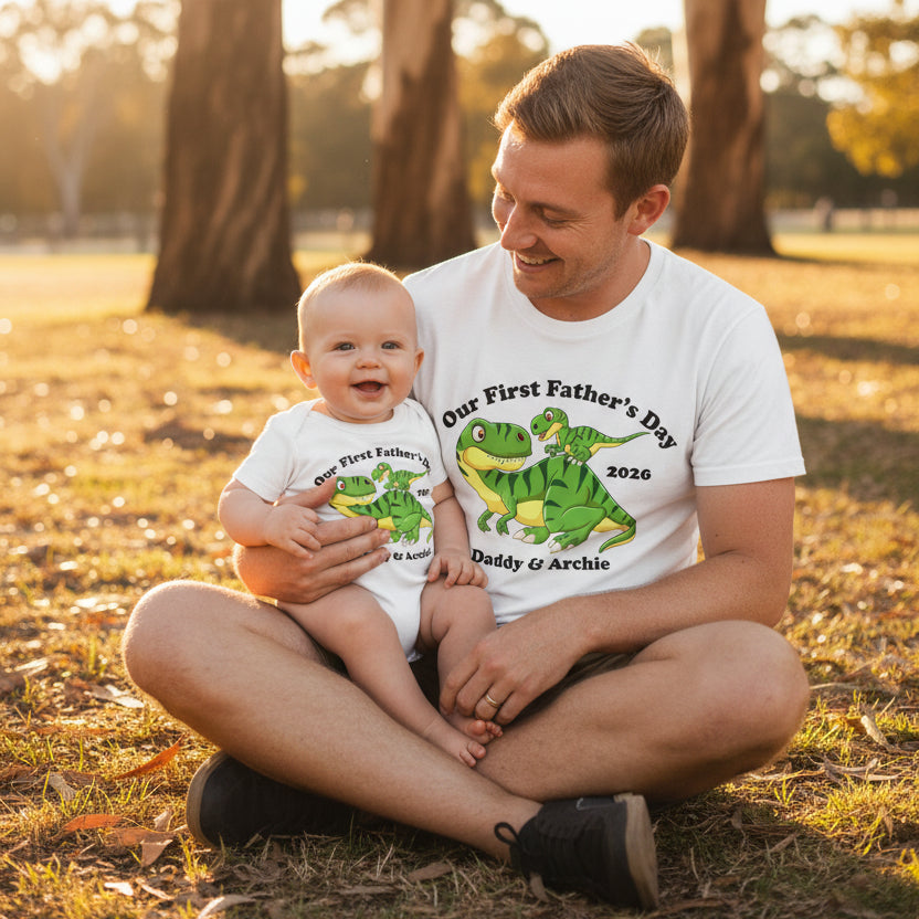 Matching white adult t-shirt and baby bodysuit with a cartoon T-Rex and baby dinosaur design reading Our First Father's Day, personalised with names and year.