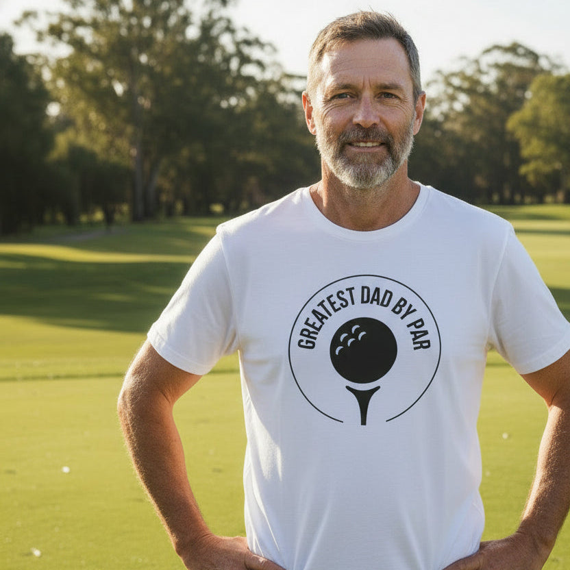 White t-shirt with a golf ball and tee emblem reading Greatest Dad By Par.