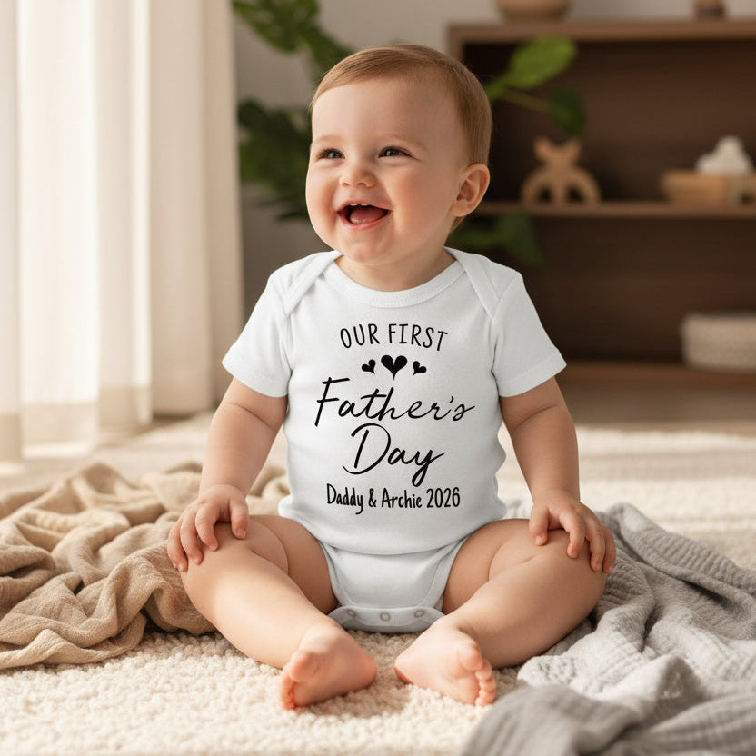 white short-sleeve baby bodysuit with Our First Father's Day script and personalised names and year.