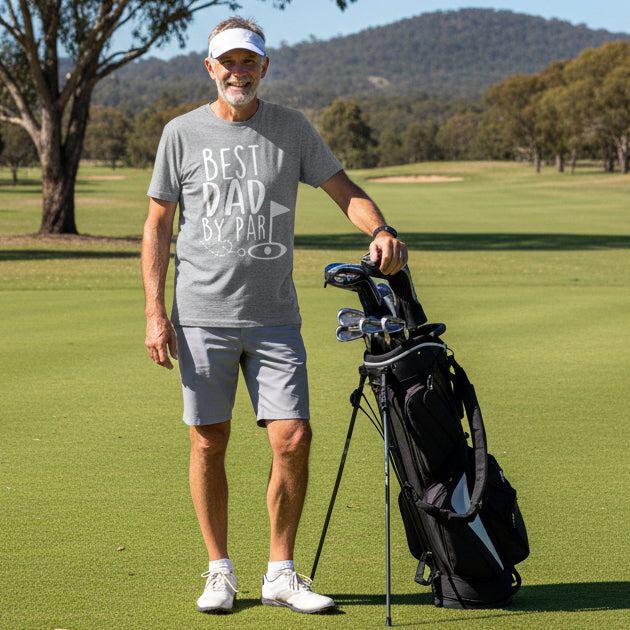 Man wearing grey Best Dad By Par t-shirt on a golf course holding clubs
