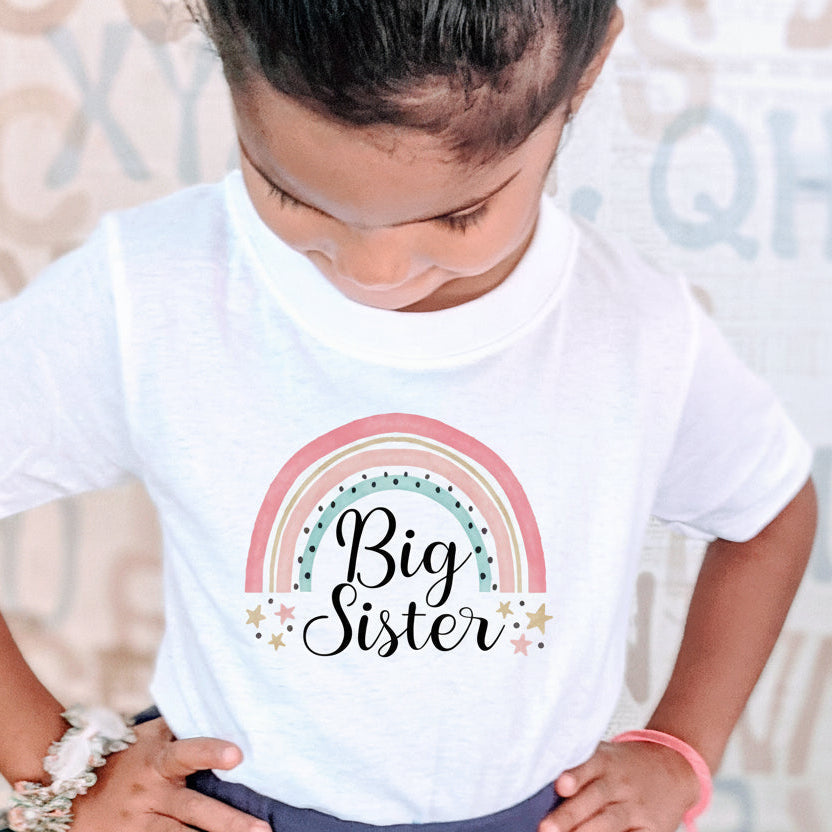 White kids t-shirt with a soft boho rainbow and the words Big Sister in black script.