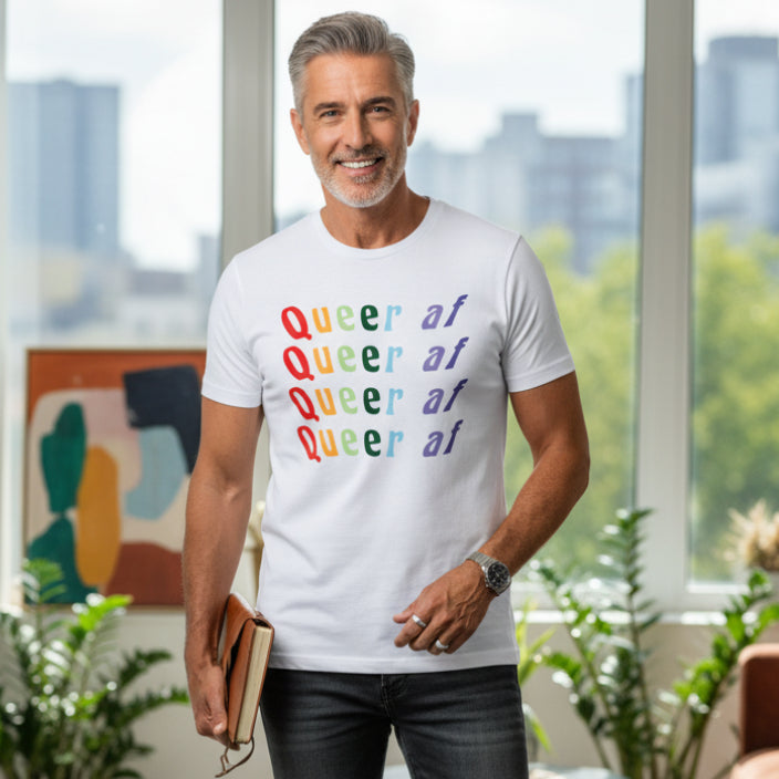 White t-shirt with 'Queer at' text in rainbow colors on a light background.