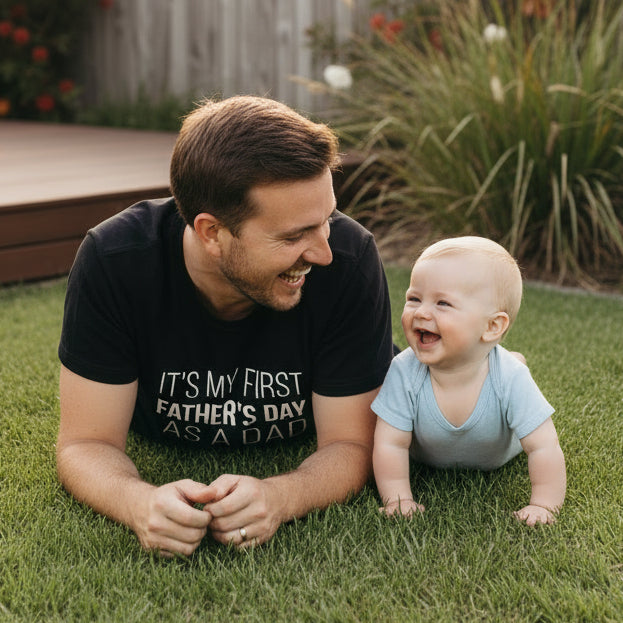 Dad wearing a black tee that reads It's My First Father's Day As A Dad.