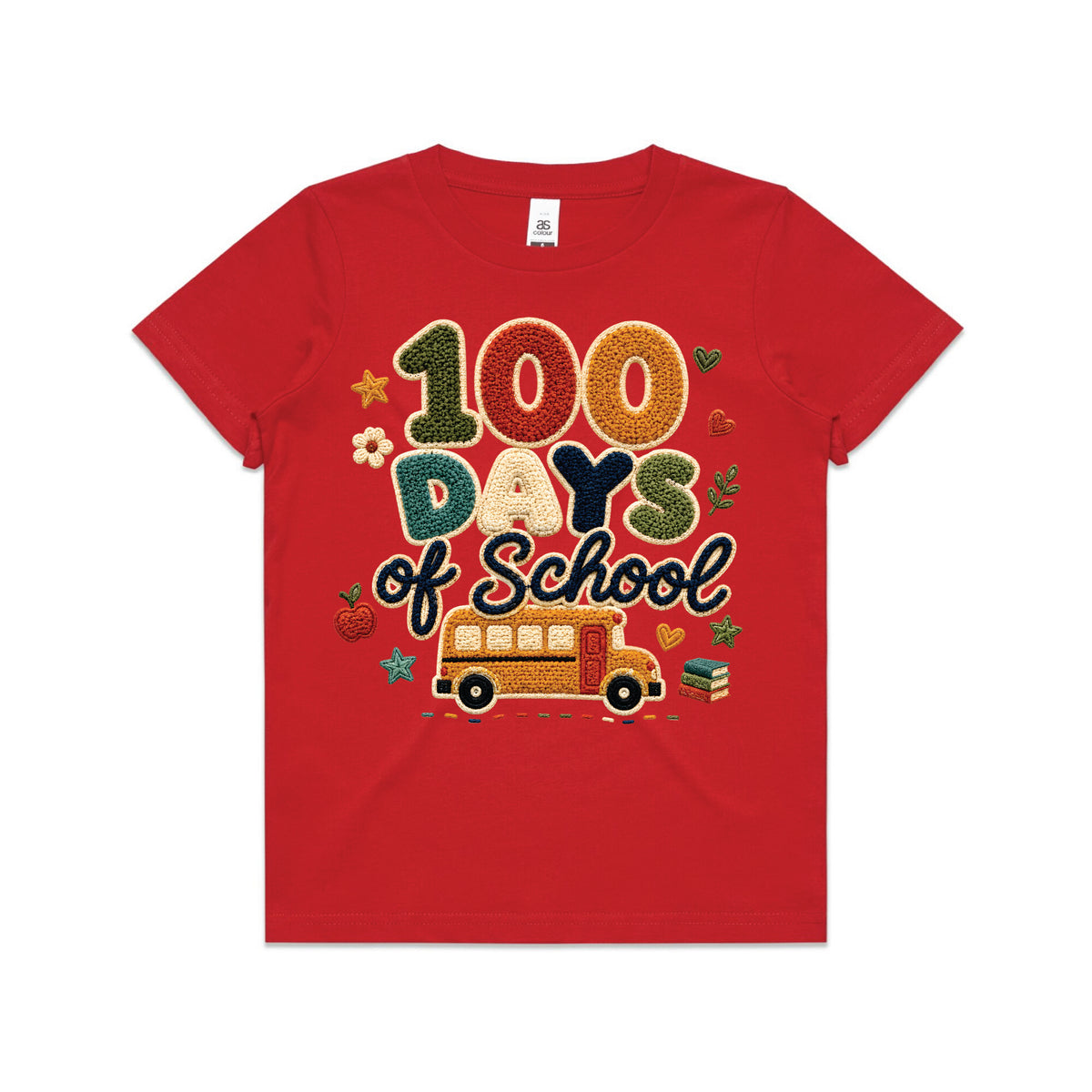 A young boy smiling in a red graphic t-shirt that reads '100 Days of School' with a school bus design, paired with denim shorts, standing on a paved driveway in front of a suburban house.