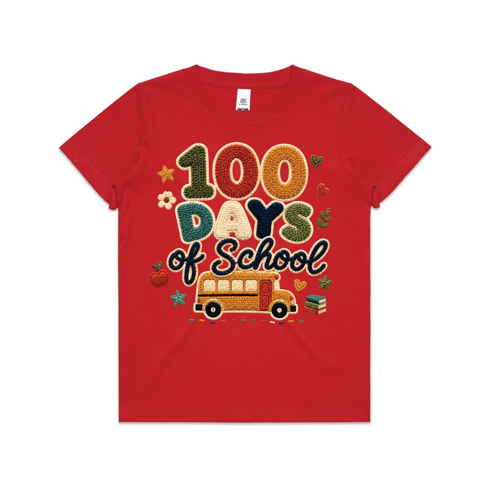 A young boy smiling in a red graphic t-shirt that reads '100 Days of School' with a school bus design, paired with denim shorts, standing on a paved driveway in front of a suburban house.
