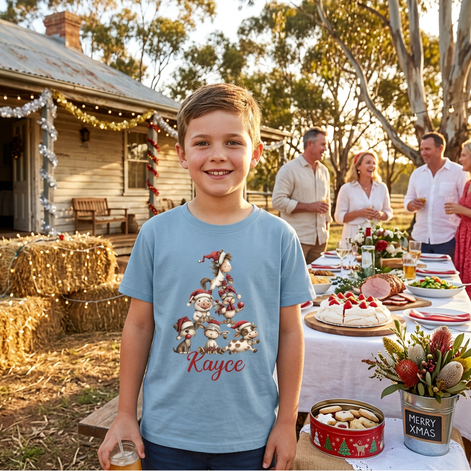 A light blue short-sleeve t-shirt with a graphic of stacked cartoon dogs wearing Santa hats arranged in a Christmas tree shape, with the name printed in red script below.