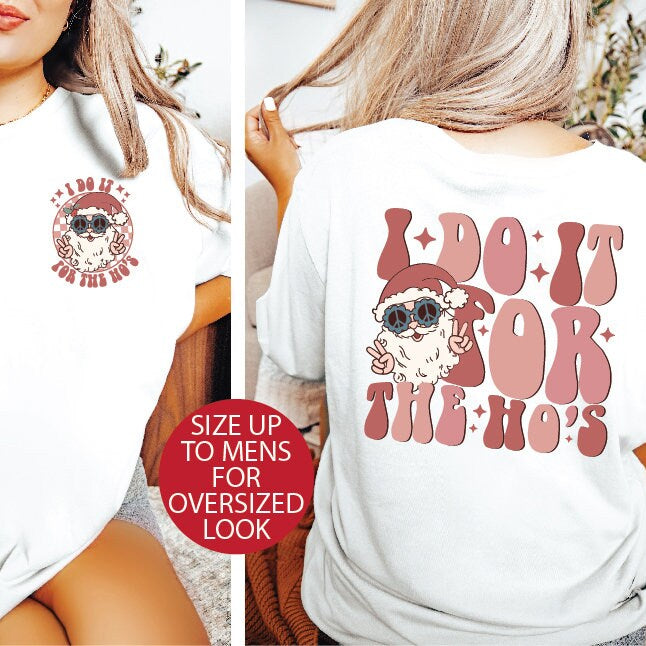 This image features a white, oversized t-shirt with a vintage-style graphic print on the front. The print depicts a playful and retro design with the phrase "I Do It For The Ho's" in bold, red lettering, accompanied by a graphic of Santa Claus wearing sunglasses and a hat.