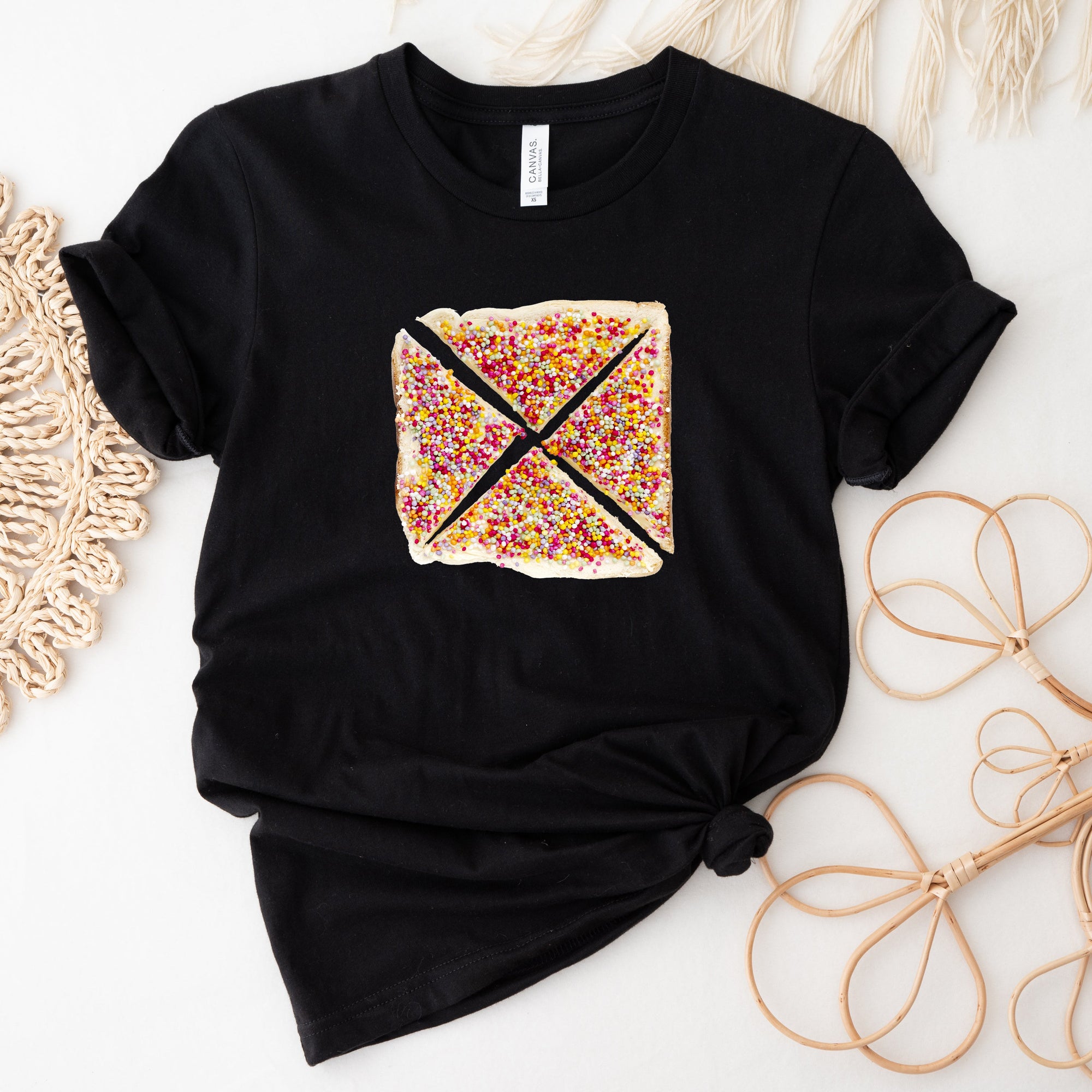 Black t-shirt with a colorful graphic design on a white surface with decorative elements.