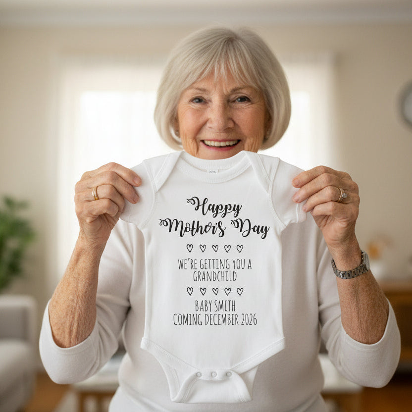 Grandmother holding personalised baby bodysuit with pregnancy announcement message for Mother’s Day reveal