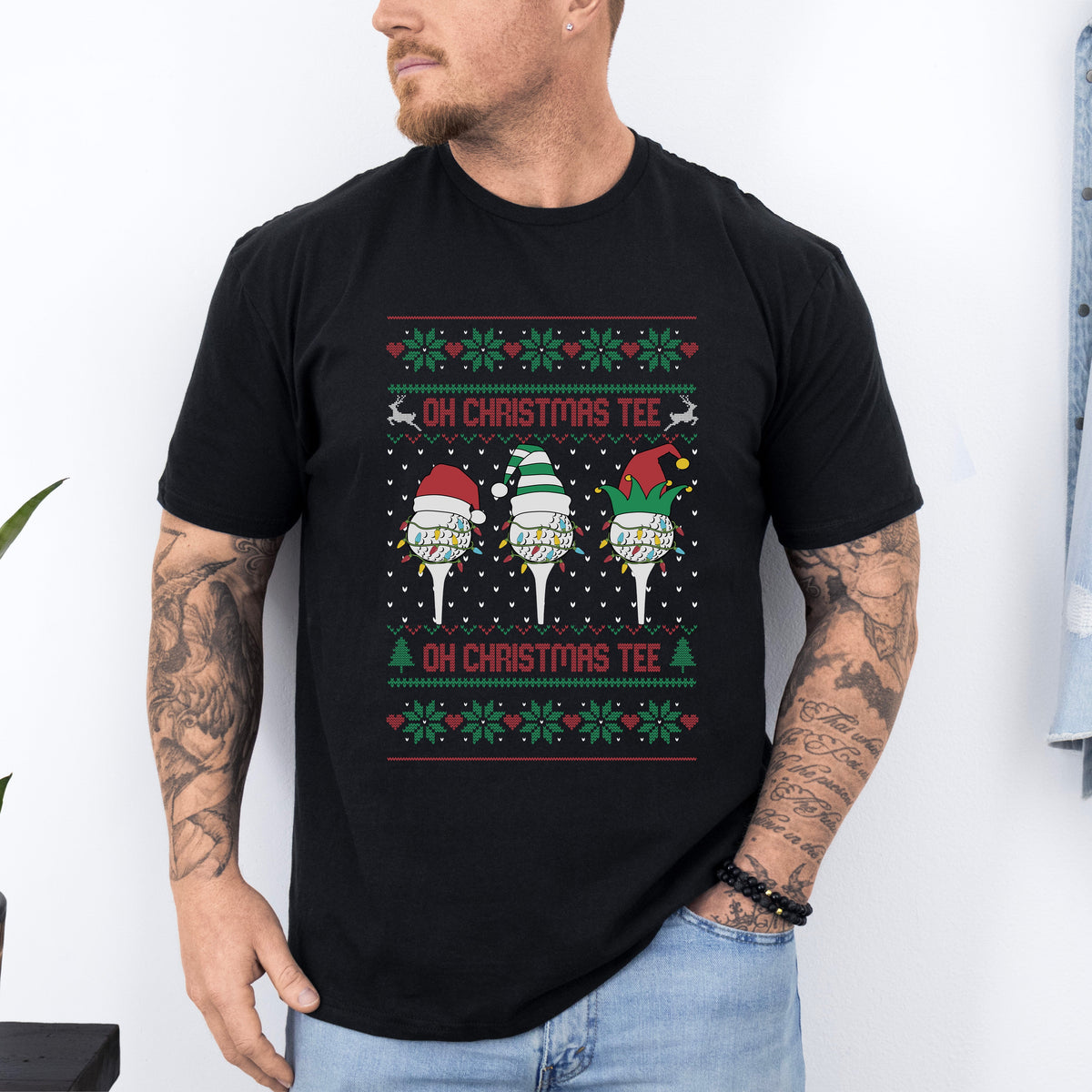 A man wearing a black Christmas-themed t-shirt with text &#39;Oh Christmas Tee&#39; and decorative elements resembling Santa Claus and a Christmas tree.