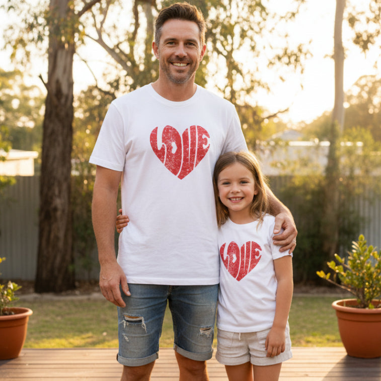 Woman and child wearing white t-shirts with red 'LOVE' heart designs on a plain background