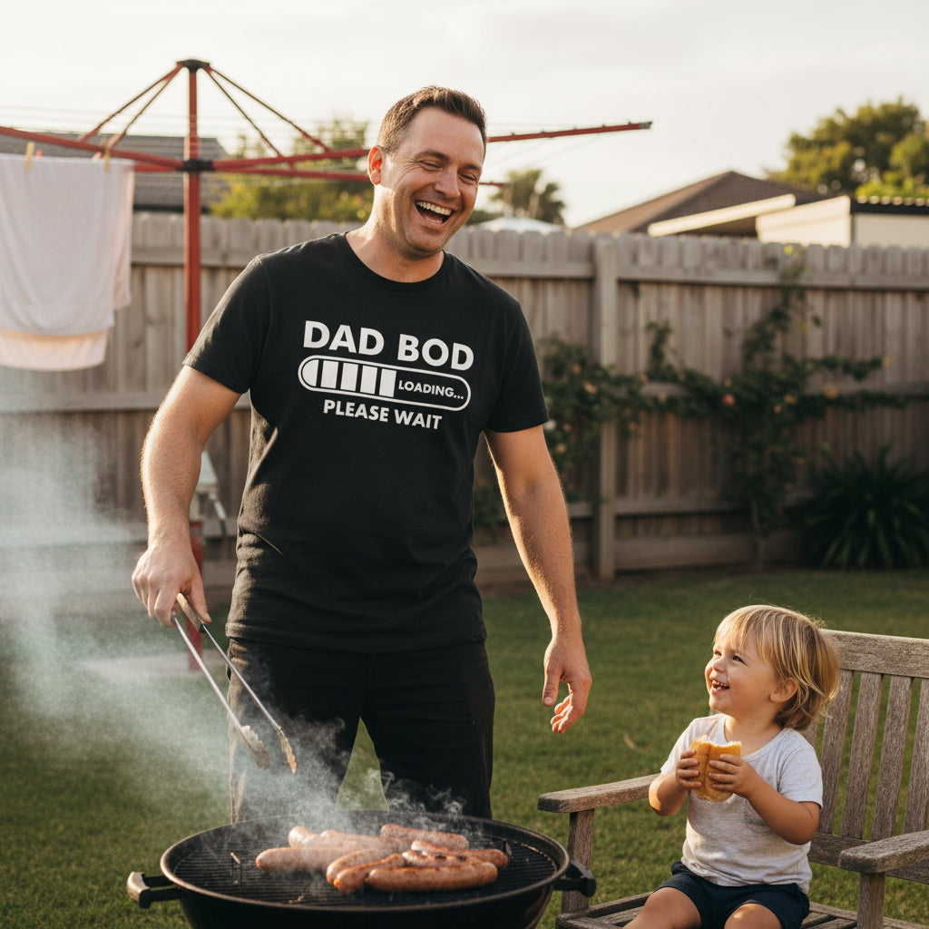 A black short-sleeve crewneck t-shirt with a white graphic print that reads 'DAD BOD' above a battery icon showing 'LOADING.