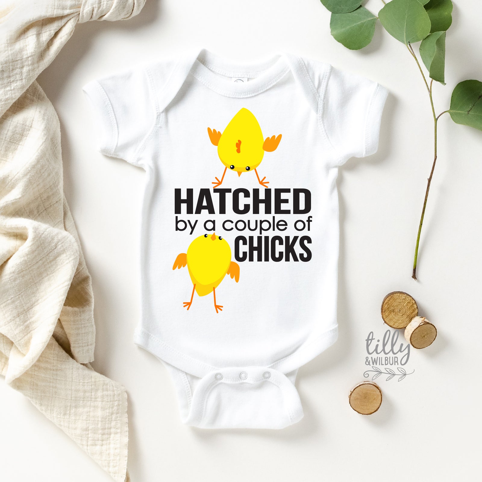 White baby onesie with yellow chicks and text on a light background