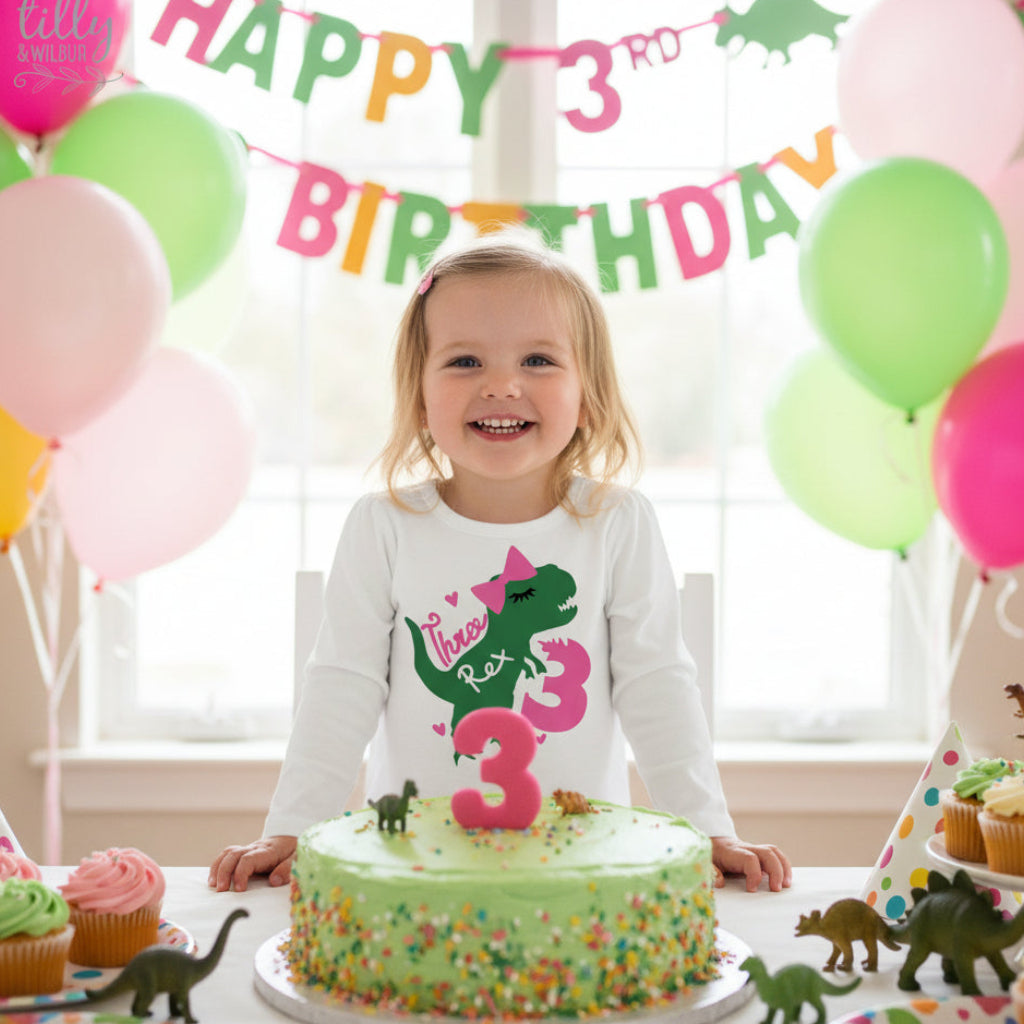 Young girl wearing a white Three Rex Girl t-shirt with green T-Rex silhouette, pink bow and eyelashes design