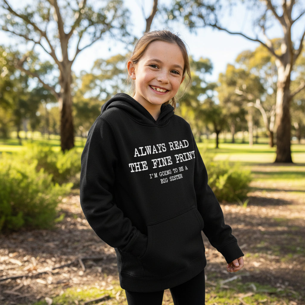 Black kids hoodie with white Always Read The Fine Print Im Going To Be A Big Sister announcement design laid flat