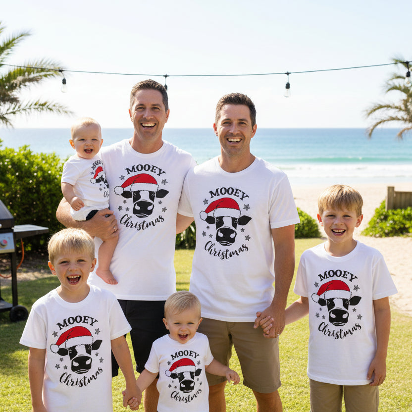 A set of white Christmas themed t-shirts for adults and children with a graphic of a cow wearing a Santa hat and the text 'MOOOY' Christmas'.
