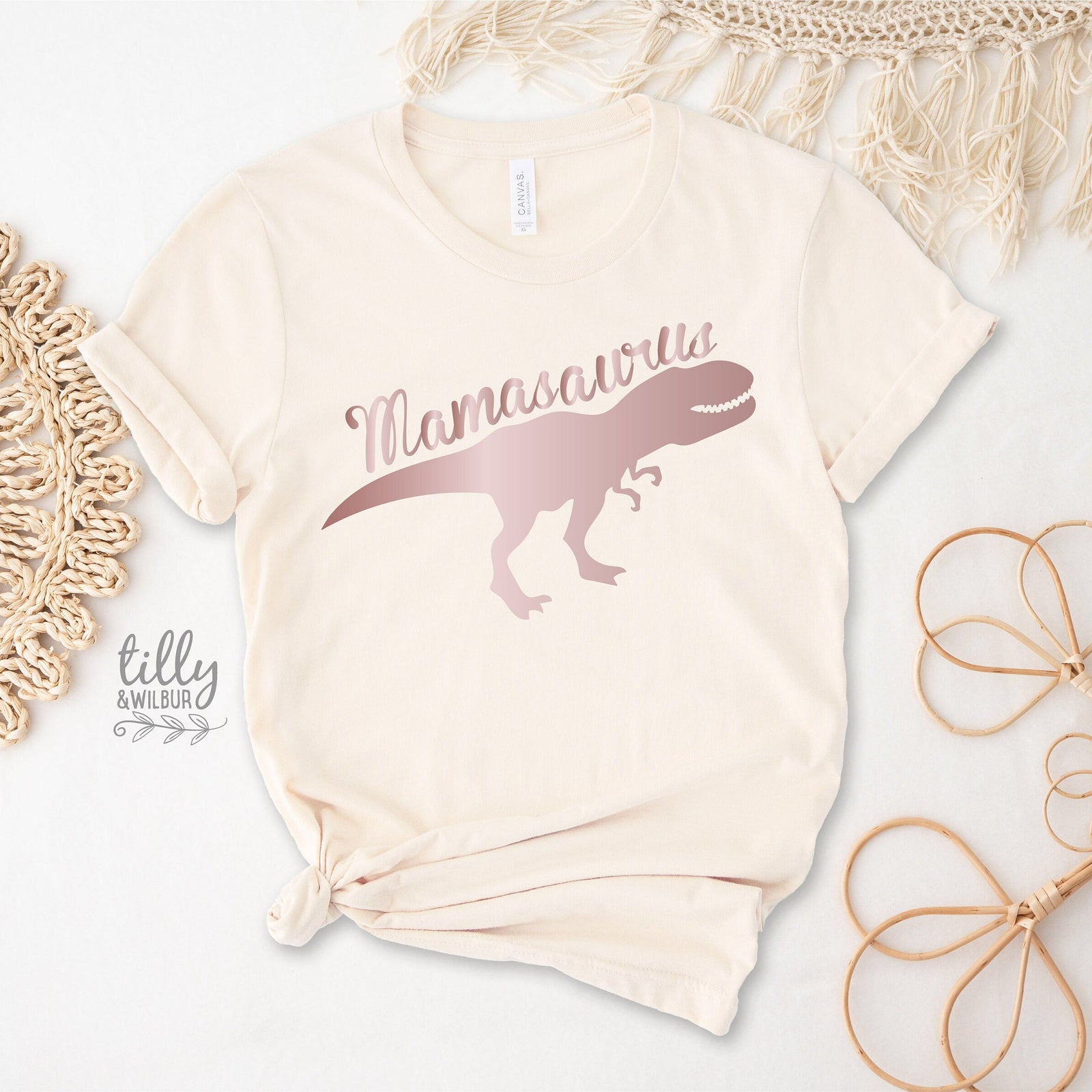 Beige t-shirt with 'Mamasaurus' design on a white surface with decorative elements.