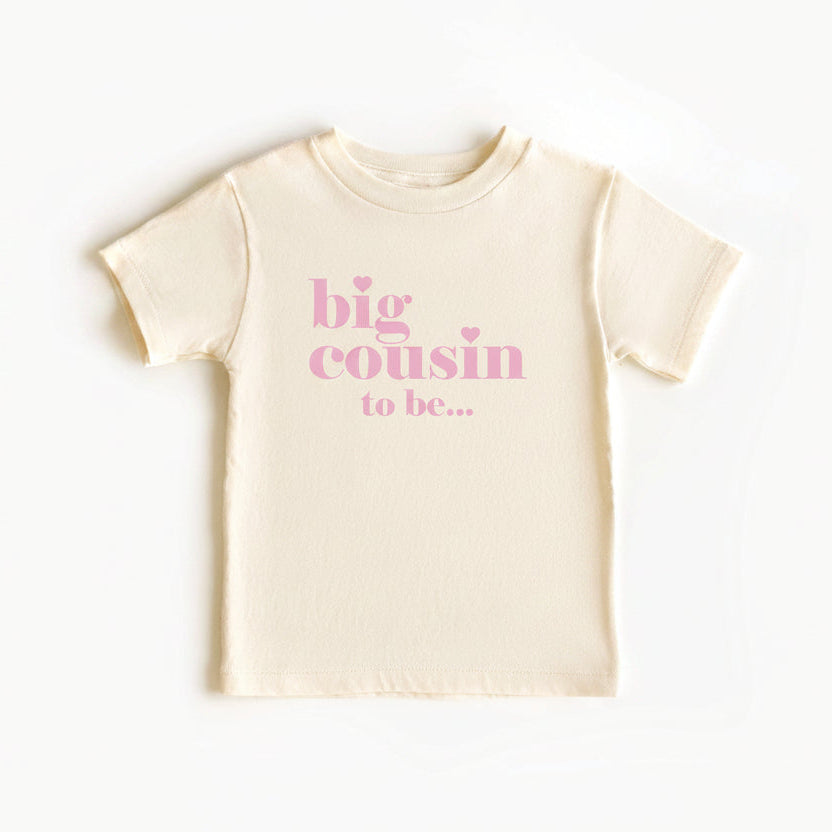 Natural coloured kids t-shirt reading big cousin to be in pink lettering with small hearts.