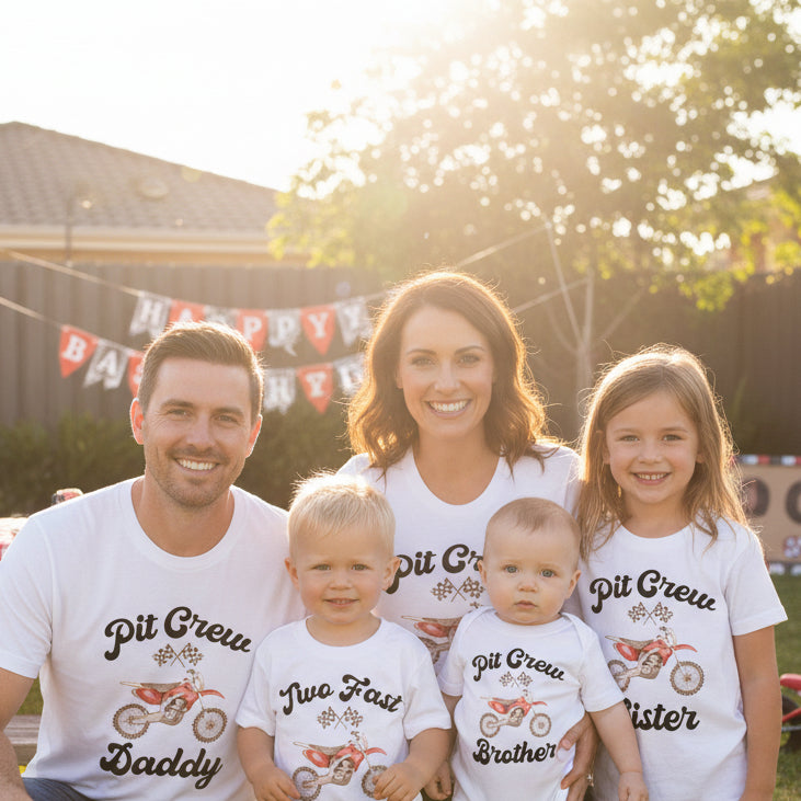Family of four celebrating a birthday with matching 'Pit Crew' shirts and a cake.