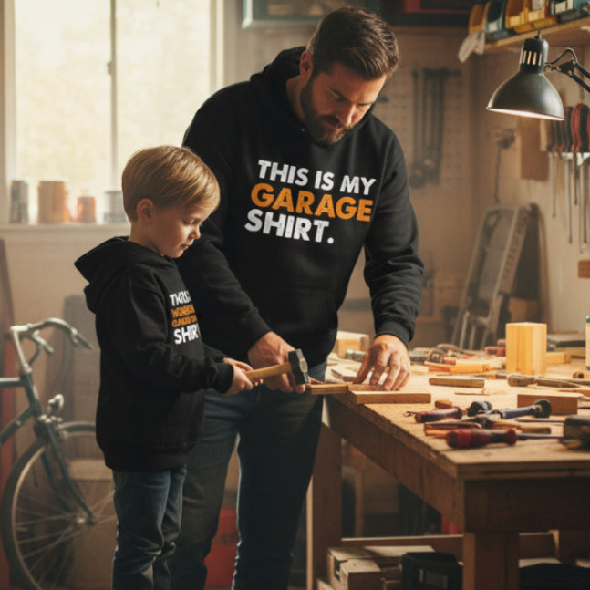 Two black t-shirts with text on a wooden surface, featuring promotional text about color and size options.
