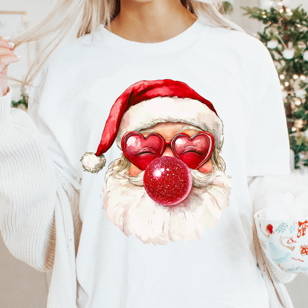 A woman wearing a white retro-style t-shirt with a 3D printed design of Santa Claus and a Christmas themed text that reads 'Babies, kids, women and men garments sizes NB-5XL and lots of colours.'.