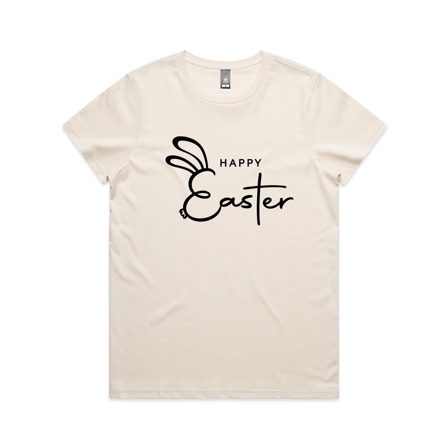 Minimalist Happy Easter bunny t-shirt in black print on natural beige shirt worn by woman on beach