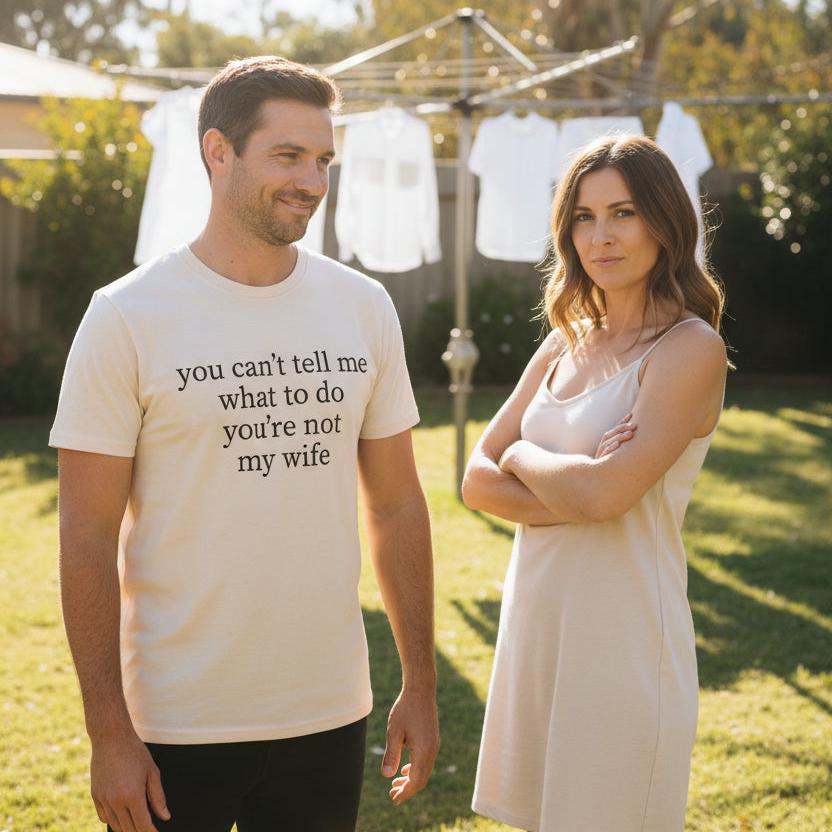 Natural cream t-shirt with black serif text reading you can&amp;#39;t tell me what to do you&amp;#39;re not my wife, displayed flat against a white background.