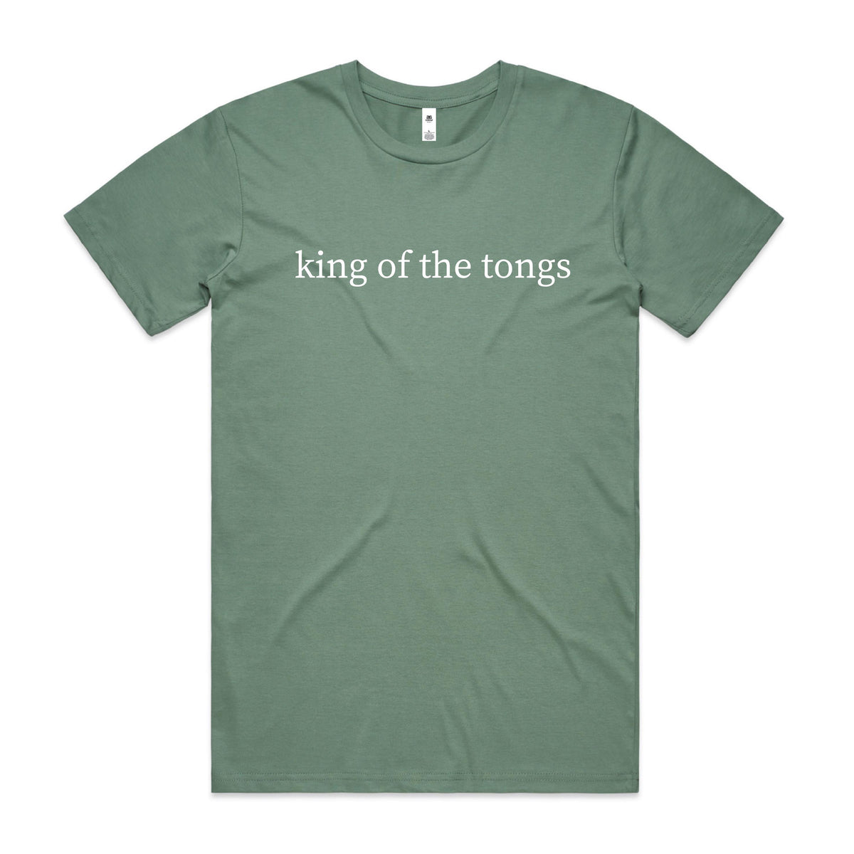 Smiling man cooking sausages on a barbecue in an Australian backyard, wearing a sage green t-shirt with white lowercase serif text reading king of the tongs.