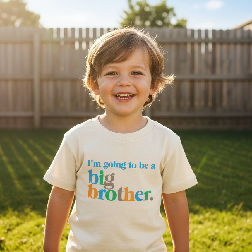 Cream kids t-shirt with multi-colour Im Going To Be A Big Brother bold serif lettering in blue, orange, green and tan
