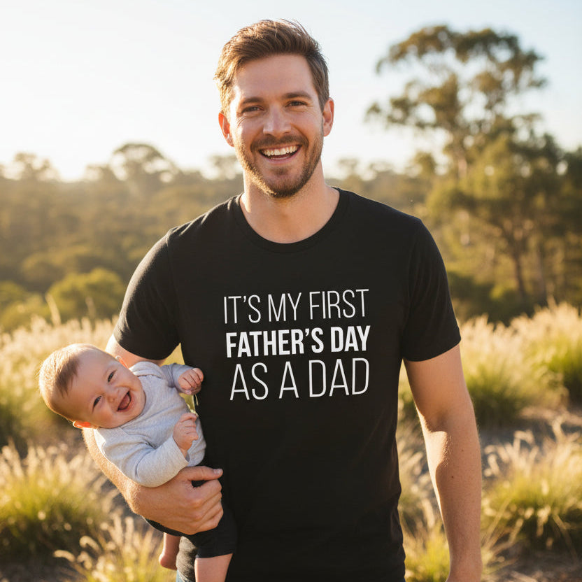 Dad wearing a black tee that reads It's My First Father's Day As A Dad.
