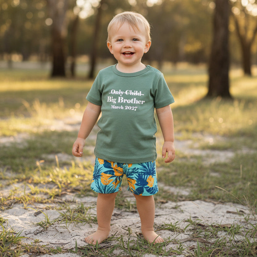 A sage green short-sleeve baby t-shirt with white printed text reading 'Only Child Big Brother March 2027' on the chest, displayed flat against a white background.