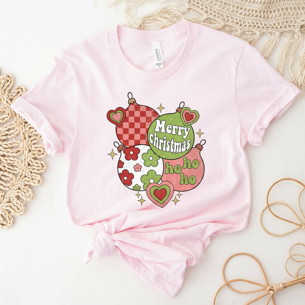 A pink Christmas-themed t-shirt with 'Merry Christmas' and 'Ho Ho Ho' text, decorated with heart and Christmas bauble designs.