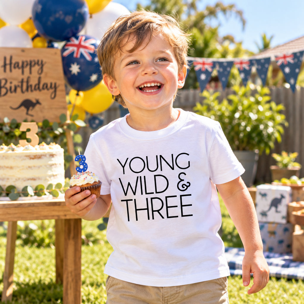 White kids t-shirt reading Young Wild and Three in bold black lettering.