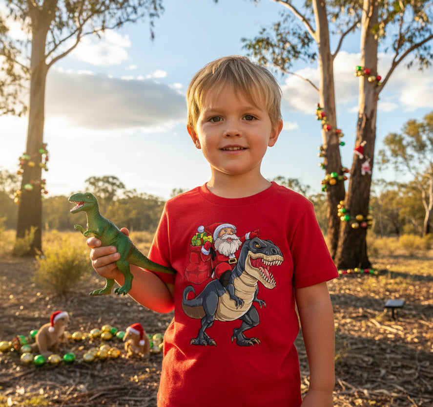 A red Christmas T-shirt with an illustration of Santa riding a dinosaur.