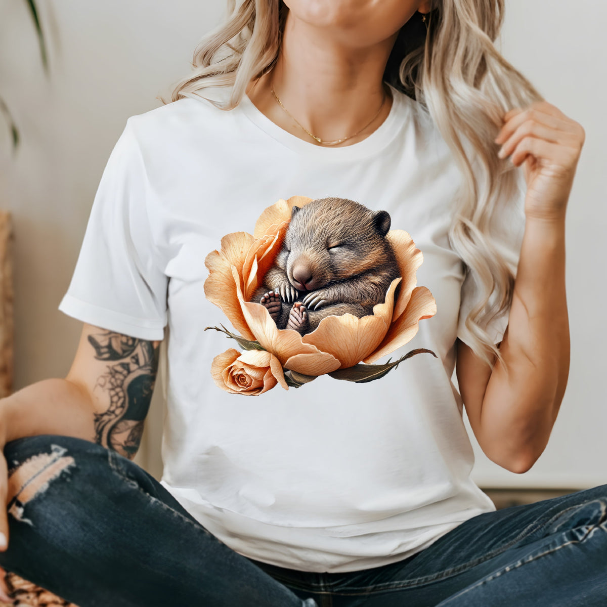 White t-shirt with a sleeping baby wombat nestled inside a peach rose.