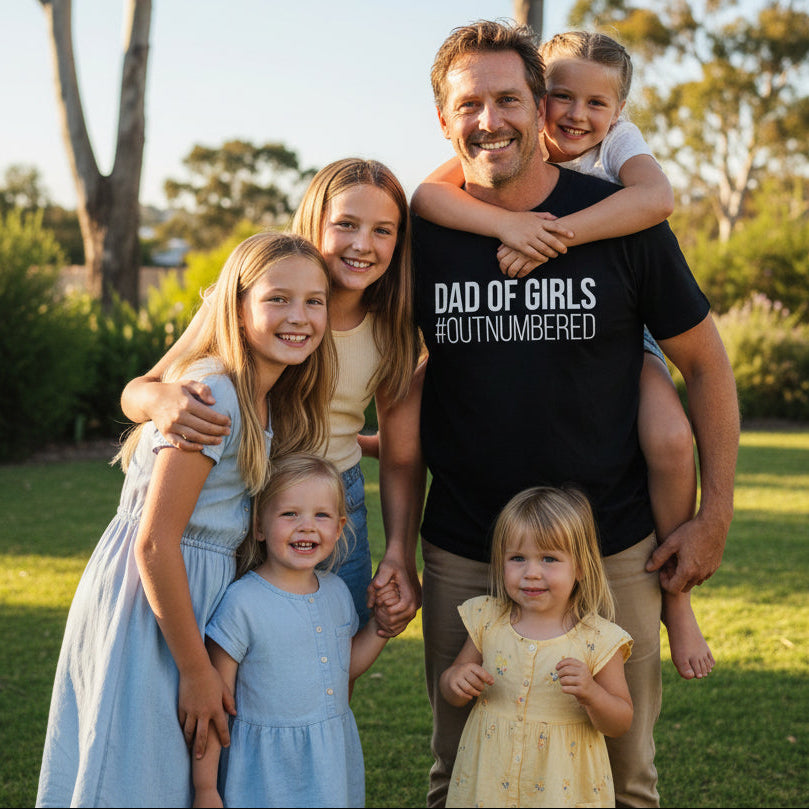 Black t-shirt with bold white text reading Dad Of Girls #Outnumbered.