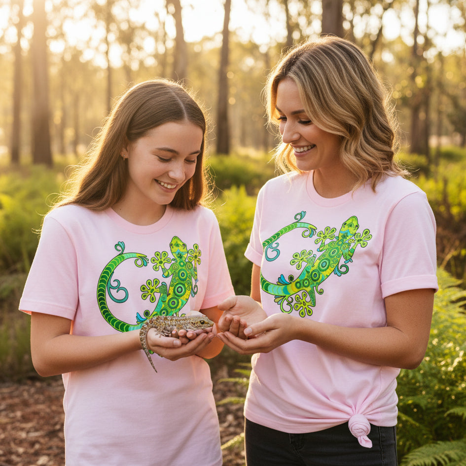 White t-shirt with a detailed vibrant green and turquoise decorative gecko illustration with swirling patterns
