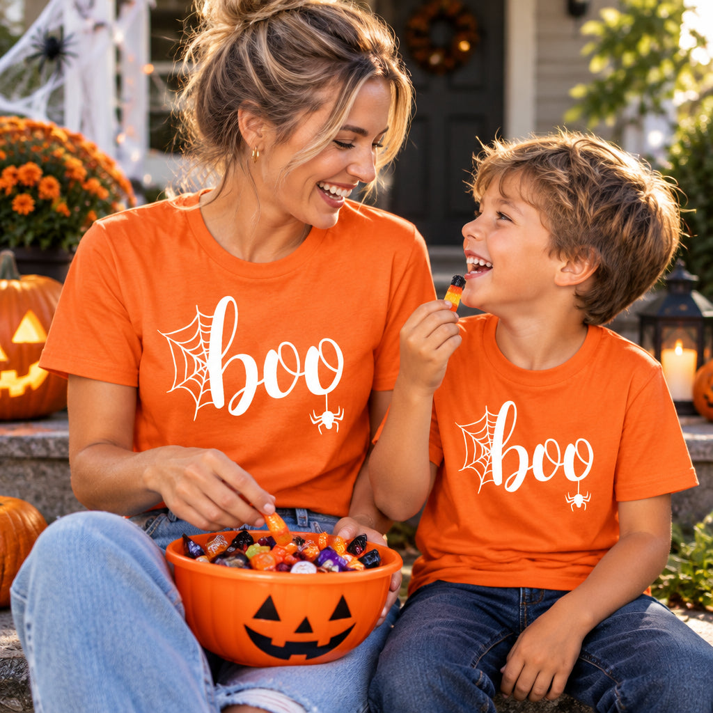 Orange t-shirt with black "boo" script lettering, spiderweb and hanging spider Halloween design